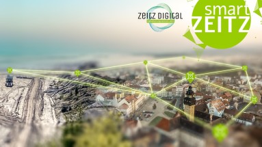 Luftaufnahme der Stadt Zeitz und des angrenzenden Kohlereviers, mit Hilfe von grünen Linien wird ein digitales Netz dargestellt, Logos von „Zeitz Digital“ und „Smart Zeitz“ am oberen Bildrand.