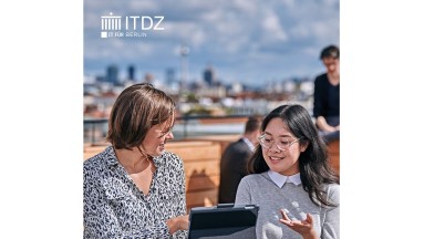 In the foreground two women with a tablet, in the background a city view of Berlin