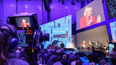 The Plaza Stage of the Smart Country Convention, people on a panel discussion, audience and a camera in the foreground