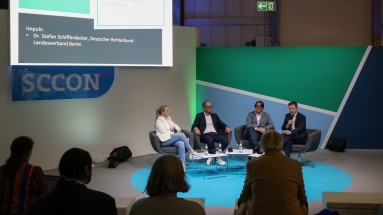 Four people in a panel discussion, with the audience in the foreground.