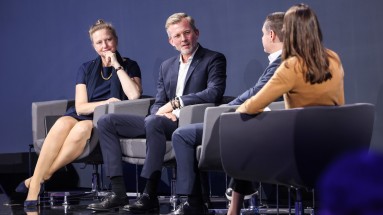 Zwei Frauen und zwei Männer sitzen auf Stühlen auf der Bühne in einer Paneldiskussion.