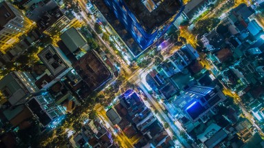 Eine Luftaufnahme einer Stadt bei Nacht, die zeigt, wie verschiedene Stadtteile durch ein Netzwerk von Straßen