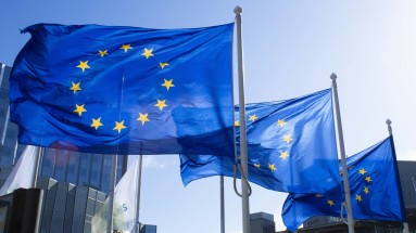 Waving EU flags, buildings in the background.